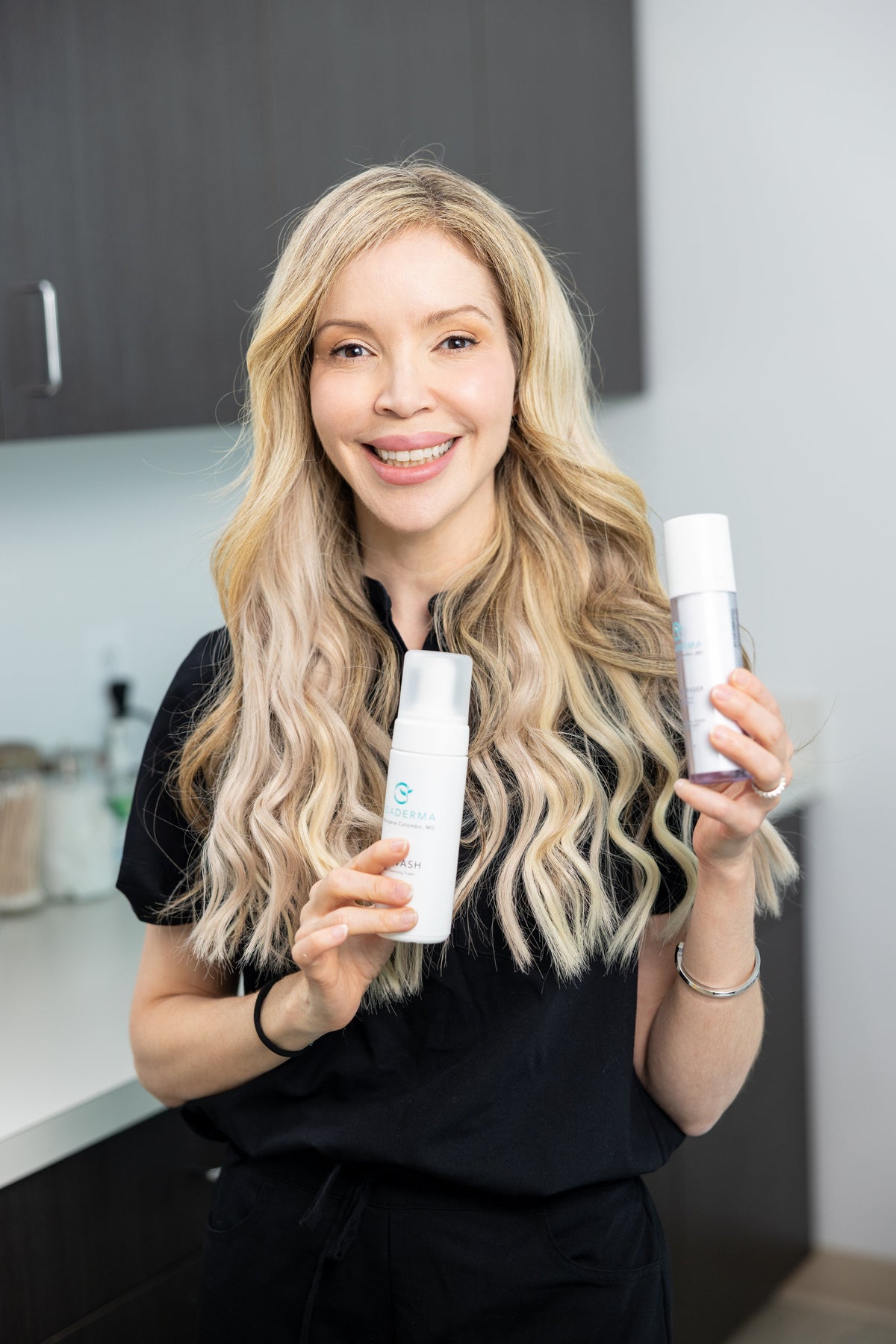 Dr. Morgana Colombo holding Vidaderma skincare products in a treatment room.